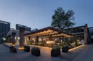 A cozy outdoor patio with a large umbrella, potted plants, and two benches, creating a welcoming atmosphere for al fresco dining