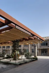A modern plaza with a metal roof, multiple windows, benches, and potted plants, conveying urban design and functionality