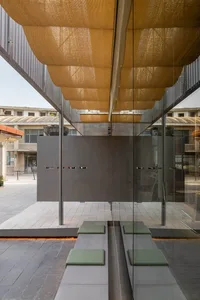 A modern lobby with a glass wall, wooden panels, and natural light, featuring two benches and a chair in a comfortable and inviting space