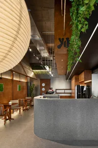 Open modern living space with chairs, a dining table, refrigerator, and sink, featuring clean lines and neutral tones