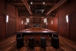 A restaurant and bar area with wooden paneling, dining tables, chairs, and lighting fixtures creating a warm and inviting atmosphere