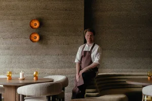 A cozy cafe interior with a stone-patterned wall, a dining table, and comfortable seating for guests
