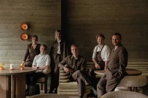A group of people posing together in a restaurant setting with multiple chairs and a relaxed atmosphere