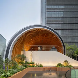 A building with a large wooden dome in front of it, surrounded by potted plants, conveying artistic expression and cultural appreciation