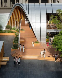 A public building with a staircase made of wood, surrounded by people walking up and down the stairs, creating a lively atmosphere