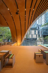 Well-lit lobby with a curved wall, benches, and dining tables, providing a comfortable space for gathering and socializing