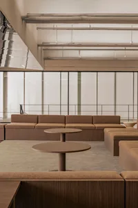 Open living space with brown couches, a chair, and natural light from a large window