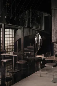 Modern restaurant interior with a black and white color scheme, featuring a dining area with tables and chairs, and a bar counter