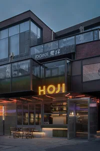 A modern Asian restaurant with glass walls, dining tables, chairs, and bottles, featuring a stylish and inviting atmosphere