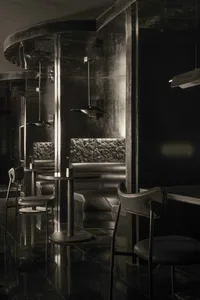 Elegant restaurant interior with multiple dining tables, chairs, a bar, and couches, featuring a black and white color scheme