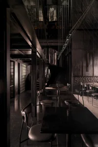 A dark and moody restaurant with black and white decor, featuring multiple tables and chairs, creating a unique ambiance
