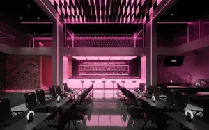 A modern bar with a long counter, stools, and pink accents, set in a restaurant atmosphere