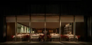 Sophisticated restaurant interior with multiple tables, chairs, and wine glasses, featuring wooden accents and a warm atmosphere