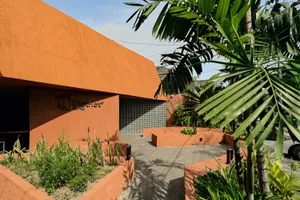 Warm and inviting building with an orange exterior, red roof, and large window, featuring two benches in front