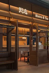 Warm and inviting bistro interior with wooden walls and flooring, featuring dining tables and chairs, and various bottles on the tables