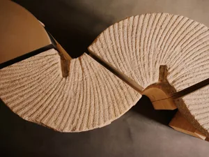 A minimalist wooden chair with a unique shape, set against a neutral background, with dramatic lighting creating depth and contrast