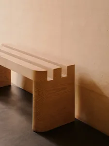 A wooden bench in a room with a cement wall, adding an industrial touch to the space