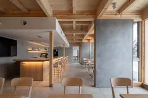 Cozy restaurant interior with wooden floors, walls, and tables, featuring comfortable seating areas and a warm atmosphere
