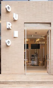 A cozy cafe interior with brick walls, tables, chairs, and a glass door entrance