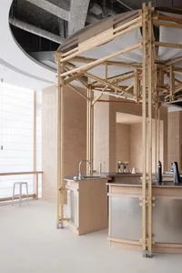 A kitchen area with a sink under a wooden structure, two bottles near the sink, and a functional yet stylish atmosphere