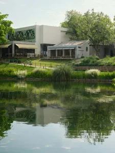 A restaurant with a patio area featuring dining tables, chairs, and umbrellas, situated next to a body of water