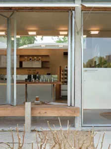 Open modern living area with a kitchen and dining room, featuring natural light, a countertop with kitchen items, and a dining table
