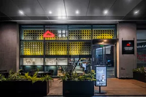 A modern coffee shop with a yellow theme, featuring a large window, chairs, a dining table, and decorative elements like potted plants and vases, creating a cozy and inviting atmosphere