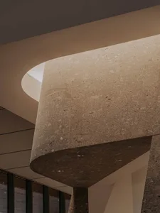A grand interior space with a curved stone wall, giving the impression of being carved from the rock itself, with a sense of historical significance