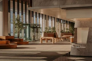 A well-lit indoor space with glass walls, benches, and potted plants, creating a comfortable and inviting atmosphere
