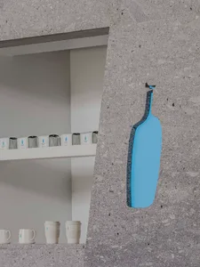 Minimalistic interior space with stone wall, two bottles mounted at different heights, and three cups near the bottom