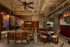 Cozy restaurant interior with wooden floors and walls, dimly lit with dining tables and chairs, creating a warm atmosphere