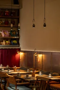 A cozy dining area in a restaurant with a long wooden table and chairs, cups and bowls on the table, and an inviting atmosphere