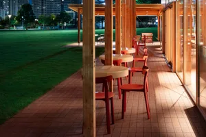 A restaurant or café outdoor dining area with multiple wooden tables and chairs, creating a comfortable seating arrangement for guests