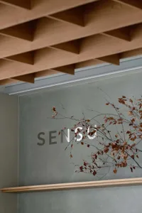Minimalist interior space with a large wooden sign reading SENSU, clean lines, and a focus on functionality
