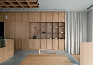 A well-organized living space with wooden walls and floors, featuring two large wooden cabinets, decorative vases, and scattered bowls, creating a warm and inviting atmosphere