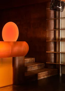 A warm and inviting interior space with a wooden and metal staircase, a large orange circle on the wall, and a cozy atmosphere
