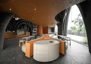A modern cafe with a counter and chairs, well-lit with natural and artificial light