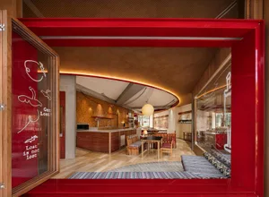 Open living area with wooden floors and walls, featuring a combined kitchen, dining, and living space with comfortable seating and dining table