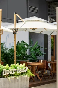 Outdoor dining area with tables and chairs under large umbrellas, surrounded by a relaxed and inviting atmosphere