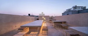 An inviting outdoor patio with multiple dining tables, benches, and chairs, perfect for social gatherings or relaxation