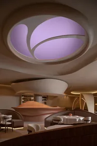 Modern restaurant interior with a large dome ceiling, chairs, couches, wine glasses, and bottles, creating a sophisticated atmosphere