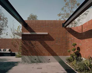 A brick building with a large archway, surrounded by trees, with a warm and traditional appearance