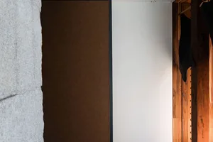A wooden door in front of a white wall, creating a warm and cozy atmosphere
