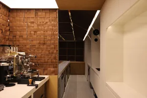 Industrial kitchen with a coffee machine, two sinks, and well-lit countertops