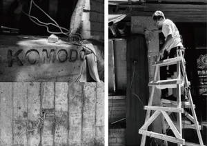 A construction site with a man working on a ladder in front of a brick wall, with two ladders and a sense of ongoing building work