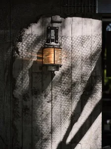 Old building with a stone wall featuring a metal lamp and a light fixture, suggesting a historical setting