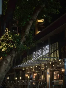 A modern restaurant with a concrete exterior, well-lit and stylish, featuring a prominent sign and inviting atmosphere