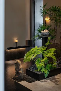 A modern room with a mix of plants, decorative vases, and a dog statue, set against a neutral background