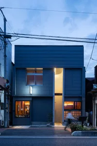 Modern house with a gray exterior, a large window, and a doorway, with bottles outside possibly indicating recent construction or renovation work