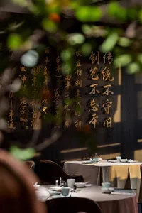 A dining table set with chairs and Chinese characters on the wall, surrounded by cups and exuding a warm and inviting atmosphere
